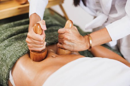 Téléchargez les photos : Une femme méconnaissable obtenant un massage anti-cellulite madérothérapie avec des tasses en bois au salon de beauté. - en image libre de droit