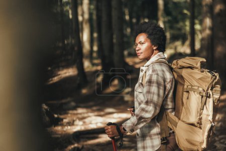 Photo for Mature black woman with backpack hiking alone through the mountains. - Royalty Free Image