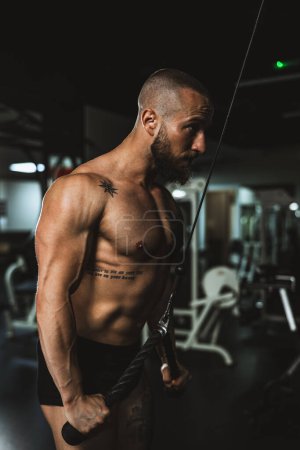 Téléchargez les photos : Un jeune homme musclé bodybuilder faire un entraînement dur pour ses muscles des bras à la salle de gym. - en image libre de droit