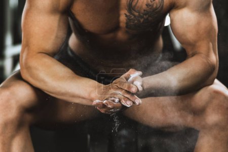 Photo for Close-up of a strong man's hands with talc getting ready to weightlifting at the gym. - Royalty Free Image