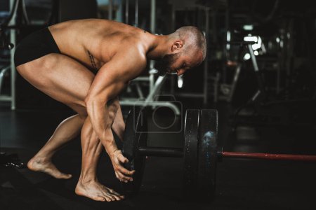 Photo for Strong muscular man preparing barbell and getting ready to weightlifting at the gym. - Royalty Free Image