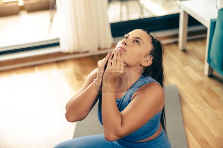 Photo for Young woman exercising at home in the morning. She is doing stretching workout. - Royalty Free Image