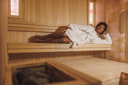 Foto de Hermosa mujer afroamericana madura disfrutando en una sauna en el centro de spa. - Imagen libre de derechos