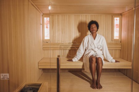 Téléchargez les photos : Belle femme mûre afro-américaine se relaxant dans un sauna au centre de spa. - en image libre de droit