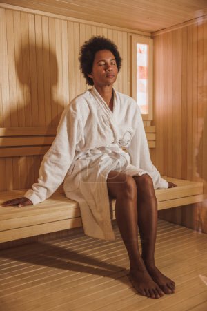 Téléchargez les photos : Belle femme mûre afro-américaine appréciant dans un sauna au centre de spa. - en image libre de droit