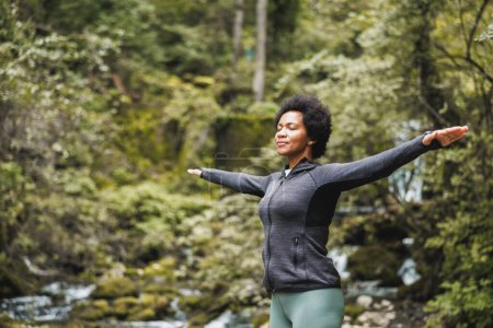 Photo for Black woman with arms outstretched taking deep breath nature and enjoying fresh air in the mountain. - Royalty Free Image
