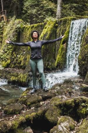 Photo for Black woman with arms outstretched taking deep breath nature and enjoying fresh air in the mountain. - Royalty Free Image