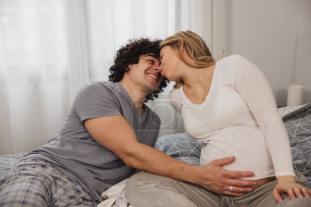 Téléchargez les photos : Heureux couple en amour communiquant tout en se relaxant sur un lit dans la chambre. - en image libre de droit