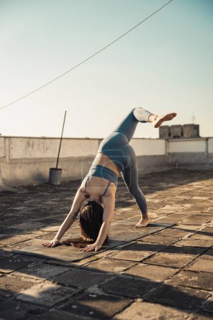Téléchargez les photos : Relaxed young woman practicing yoga on a rooftop terrace. - en image libre de droit