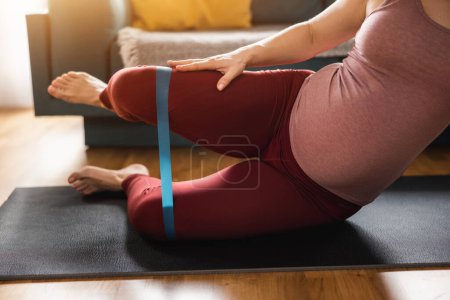 Téléchargez les photos : Prise de vue d'une femme enceinte méconnaissable faisant de l'exercice à la maison. Elle fait de l'exercice de mobilité. - en image libre de droit