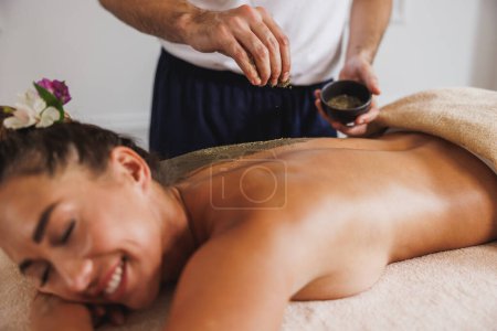 Photo for Beautiful young woman enjoying a seaweed mud massage treatment at the beauty salon. - Royalty Free Image
