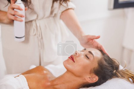 Photo for Beautiful young woman enjoying a facial treatment at the beauty salon. - Royalty Free Image