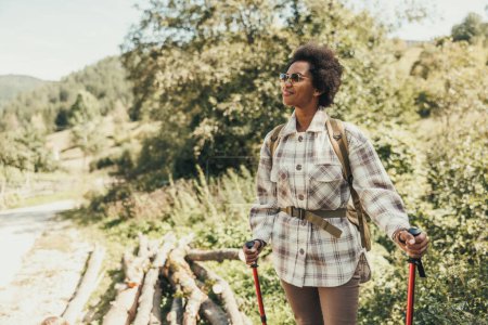 Photo for Mature black woman enjoying the view of the forest while hiking in nature. - Royalty Free Image