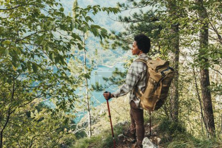 Foto de Madura mujer negra de pie en la cima de una colina y disfrutar de la vista durante su caminata en las montañas. - Imagen libre de derechos