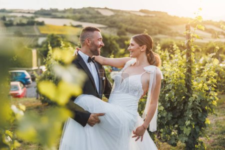 Téléchargez les photos : Tourné d'un jeune couple heureux dansant dans le vignoble au coucher du soleil le jour de leur mariage. - en image libre de droit