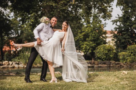 Foto de Foto de una feliz pareja joven divirtiéndose y bailando en el parque el día de su boda. - Imagen libre de derechos