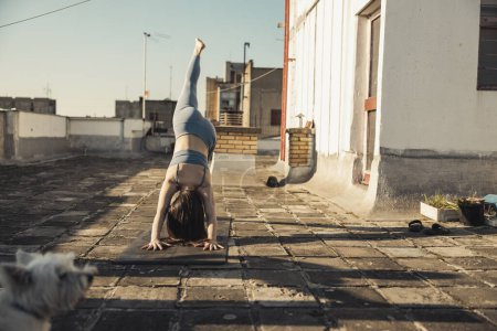 Photo for Relaxed young woman practicing yoga on a rooftop terrace. - Royalty Free Image