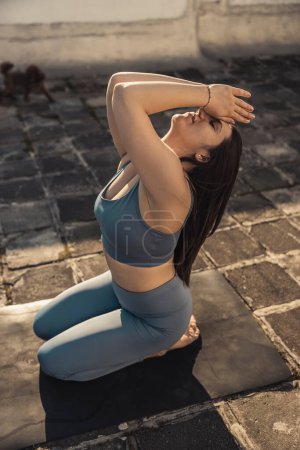 Photo for Relaxed young woman practicing yoga on a rooftop terrace. - Royalty Free Image
