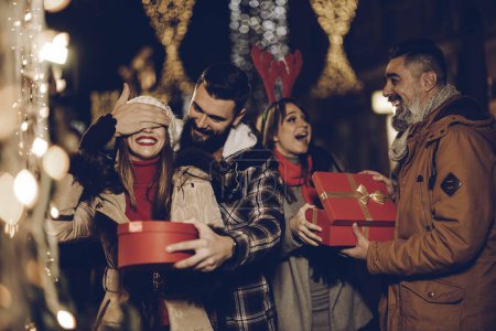 Téléchargez les photos : Tourné d'un groupe de jeunes amis joyeux avec des cadeaux de Noël s'amuser à une soirée. - en image libre de droit