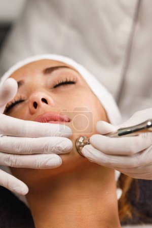 Téléchargez les photos : Tournage d'une belle jeune femme sur un traitement facial de microdermabrasion au salon de beauté. - en image libre de droit