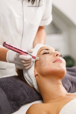 Photo for Shot of a beautiful young woman on a facial dermapen micro-needling treatment at the beauty salon. - Royalty Free Image