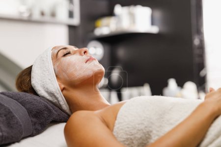 Foto de Foto de una hermosa joven recibiendo un tratamiento de mascarilla facial en el salón de belleza. - Imagen libre de derechos