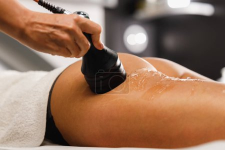 Foto de Foto de una mujer irreconocible recibiendo un masaje anti celulitis en el salón de belleza. Ella tiene un tratamiento de vacío para la reducción de grasa. - Imagen libre de derechos