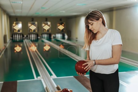 Foto de Shot of a cute young woman holding bowling ball in the bowling club - Imagen libre de derechos