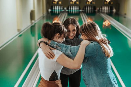 Téléchargez les photos : Trois gaies joueuses de bowling s'amusent et célèbrent la victoire au club de bowling. - en image libre de droit