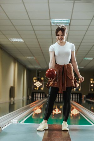 Téléchargez les photos : Tourné d'une jolie jeune femme tenant une boule de bowling au club de bowling. - en image libre de droit