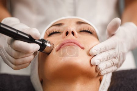 Téléchargez les photos : Tournage d'une belle jeune femme sur un traitement de mésothérapie faciale sans aiguille au salon de beauté. - en image libre de droit