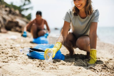 Foto de Voluntarios limpiando la playa del mar recogiendo basura en bolsas de plástico. - Imagen libre de derechos