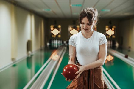Foto de Shot of a cute young woman holding bowling ball at the bowling club. - Imagen libre de derechos