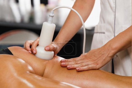 Foto de Foto de una mujer irreconocible recibiendo un masaje anti celulitis en el salón de belleza. Ella tiene un tratamiento de cavitacion por ultrasonido para reducir la grasa. - Imagen libre de derechos