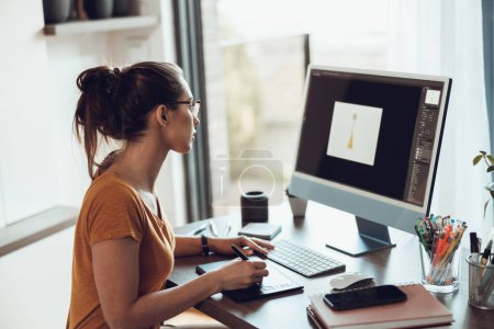 Photo for Creative young woman looking thoughtful while working on computer from her home office. - Royalty Free Image