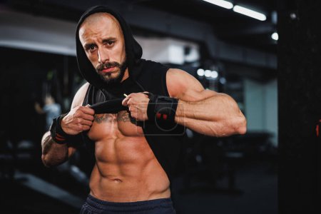 Photo for Shot of a young fitness man showing his perfect muscles while posing after working out at the gym. Looking at camera. - Royalty Free Image