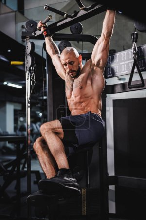 Téléchargez les photos : Un jeune musclé bodybuilder homme faisant des orteils pour bar exercice à la salle de gym. - en image libre de droit