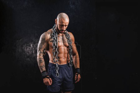 Téléchargez les photos : Prise de vue d'un jeune homme de fitness debout dans la salle de gym et posant avant de s'entraîner avec une lourde chaîne autour du cou. - en image libre de droit