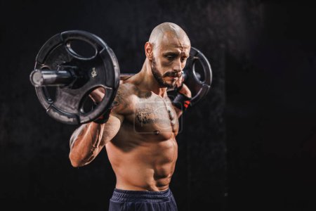 Téléchargez les photos : Prise de vue d'un bodybuilder musclé faisant un entraînement dur avec un haltère pour ses muscles de l'épaule à la salle de gym. - en image libre de droit