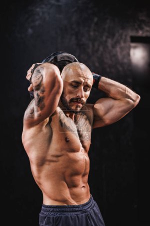 Foto de Hombre musculoso fuerte mostrando sus músculos perfectos después de hacer ejercicio con placa de peso en el gimnasio. - Imagen libre de derechos