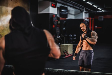 Photo for Shot of a young fitness man showing his perfect abs muscles in front of a mirror in the gym. - Royalty Free Image