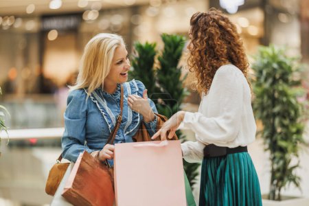 Téléchargez les photos : Plan recadré de deux belles femmes souriantes profitant d'une journée de shopping dans un centre commercial de la ville. - en image libre de droit