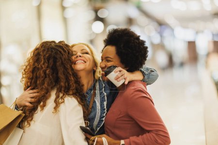 Foto de Hermosa mujer sonriente abrazando a sus mejores amigos en el centro comercial de la ciudad durante la reunión en una juerga de compras. - Imagen libre de derechos