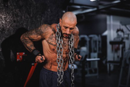 Photo for Shot of a young fitness man working out with a heavy chain around his neck in the gym. - Royalty Free Image