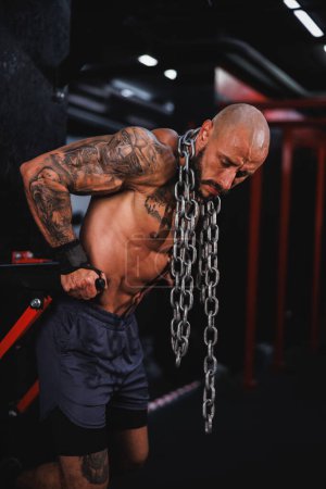 Photo for Shot of a young muscular bodybuilder performing dips with a heavy chain around his neck in the gym. - Royalty Free Image