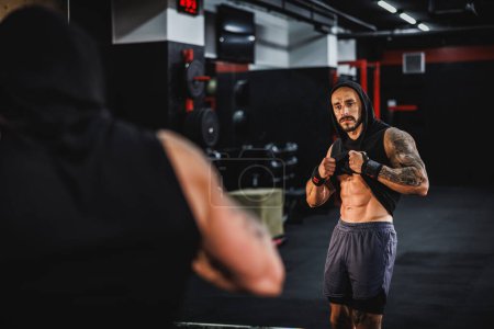 Foto de Foto de un joven musculoso parado frente a un espejo y mostrando su perfecto pack de seis después de hacer ejercicio en el gimnasio. - Imagen libre de derechos