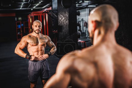 Photo for Shot of a young muscular bodybuilder showing his perfect muscles in front of a mirror at the gym. - Royalty Free Image