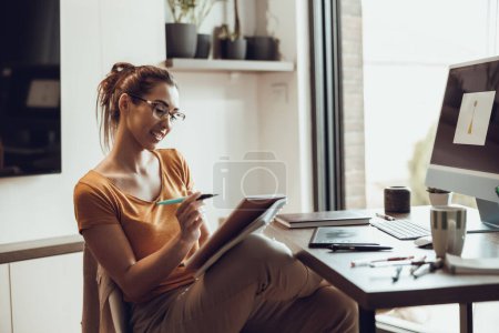 Photo for Young female designer working on computer from her home office. - Royalty Free Image
