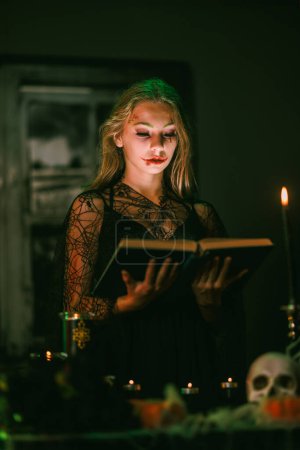 Foto de Retrato de una linda adolescente con un enorme libro viejo que se está preparando para Halloween. - Imagen libre de derechos