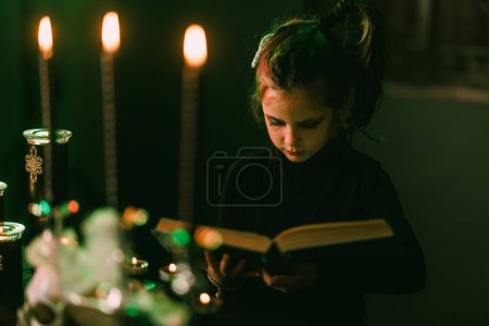 Photo for Cute Halloween little girl who is reading huge old book. - Royalty Free Image